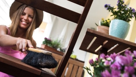 Balkon fit für den Frühling machen: Eine junge Frau macht mit einem Handbesen Gartenmöbel sauber. (Foto: picture-alliance / Reportdienste, Picture Alliance) Balkon fit für den Frühling machen: Eine junge Frau macht mit einem Handbesen Gartenmöbel sauber.