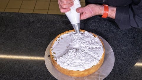 Mit einer Sterntülle wird der Eischnee so auf den Rhabarberkuchen gespritzt, dass einzelnen Stücke aus Baiser entstehen. (Foto: SWR, Corinna Holzer)