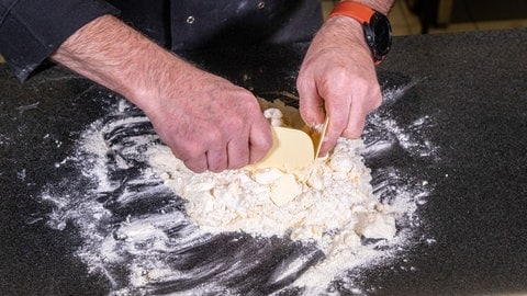 Ein feiner Boden für den Rhabarberkuchen: Den Mürbteig vermengt man auf der Arbeitsfläche mit Teigschabern. (Foto: SWR, Corinna Holzer) Ein feiner Boden für den Rhabarberkuchen: Den Mürbteig vermengt man auf der Arbeitsfläche mit Teigschabern.