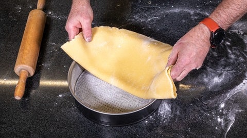 Der ausgerolle Boden aus Mürbteig für den Rhabarberkuchen kommt in die vorbereitete Springform. (Foto: SWR, Corinna Holzer)