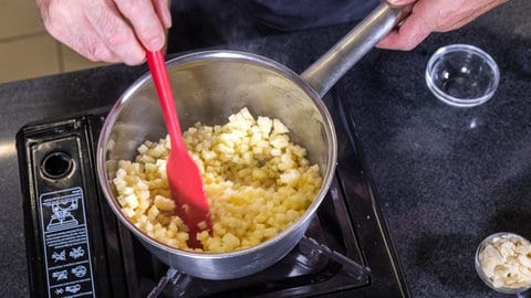 Joachim Habiger rührt in einem Topf auf dem Herd die Äpfel: Für diese Apfeltaschen aus Hefeteig wird die Füllung aus Äpfeln, Butter und Zucker zunächst erhitzt.