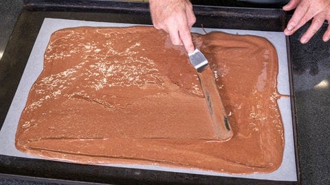Rezept für Schwarzwälder Kirsch als Rolle: Der flüssige Biskuitteig wird auf ein Backpapier gestrichen. (Foto: SWR, Corinna Holzer) Rezept für Schwarzwälder Kirsch als Rolle: Der flüssige Biskuitteig wird auf ein Backpapier gestrichen.