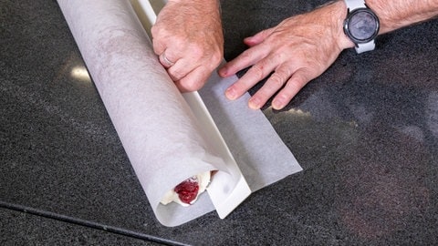 Rezept für Schwarzwälder Kirsch als Rolle: Die Kirschrolle wird mit Hilfe eines Backpapiers zusammengerollt. (Foto: SWR, Corinna Holzer) Rezept für Schwarzwälder Kirsch als Rolle: Die Kirschrolle wird mit Hilfe eines Backpapiers zusammengerollt.