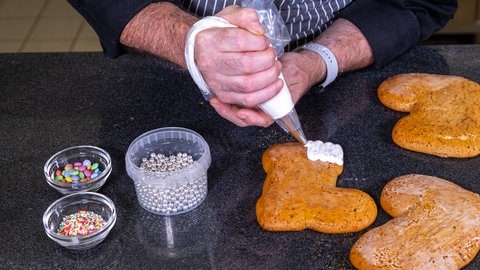 Nikolausstiefel backen: Auf den oberen Rand der Stiefel wird der Zuckerguss mit einer Spritztüte aufgetragen. (Foto: SWR, Corinna Holzer) Nikolausstiefel backen: Auf den oberen Rand der Stiefel wird der Zuckerguss mit einer Spritztüte aufgetragen.