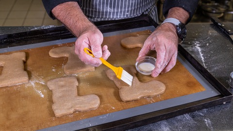 Nikolausstiefel backen: Die ausgestochenen Stiefel werden mit Glasur bestrichen. (Foto: SWR, Corinna Holzer) Nikolausstiefel backen: Die ausgestochenen Stiefel werden mit Glasur bestrichen.