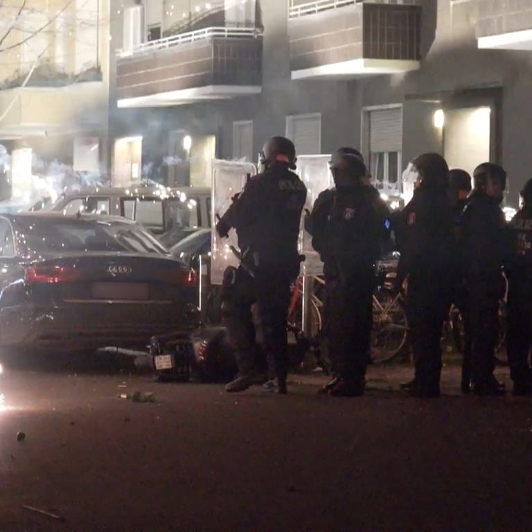 Polizeibeamte stehen hinter explodierendem Feuerwerk in Berlin. Nach Angriffen auf Einsatzkräfte in der Silvesternacht hat die Diskussion um Konsequenzen begonnen. Berlins Regierende Bürgermeisterin will, dass sich die Innenminister mit dem Thema beschäftigen.