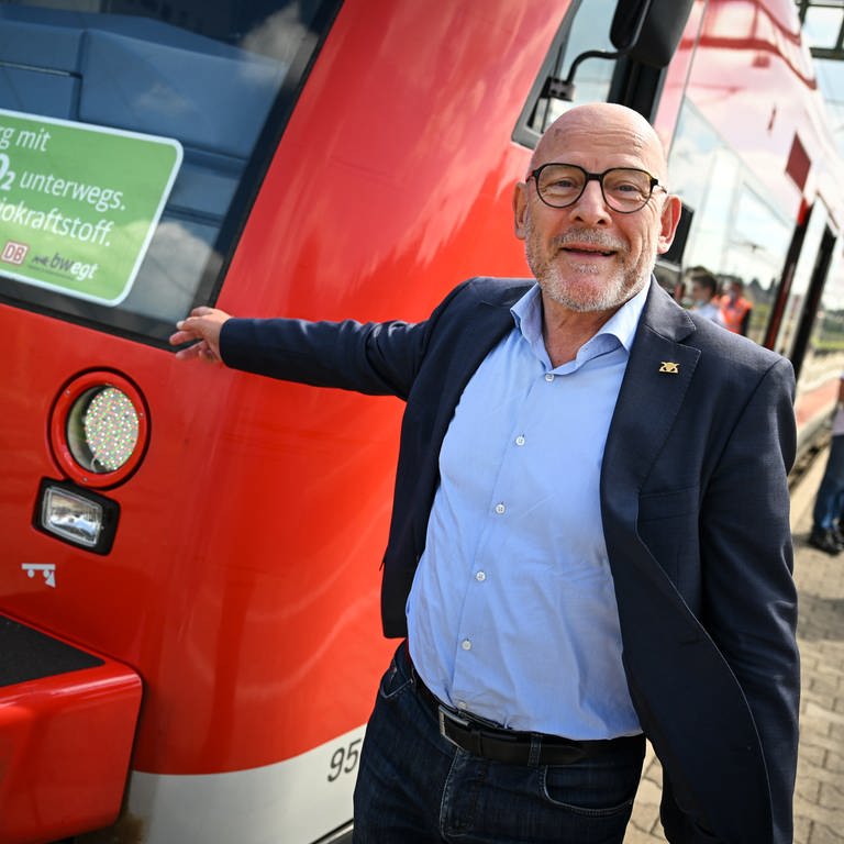 Winfried Hermann, Verkehrsminister von Baden-Württemberg, steht neben dem Regionalzug, der als bundesweit erster mit Biokraftstoff betankt werden soll.
