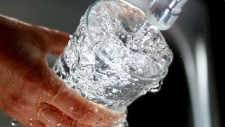 Trinkwasser läuft in ein Glas. Wasserwerke am Rhein warnen vor einer Belastung durch Chemikalie TFA.