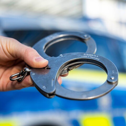 Handschellen vor einem Polizeiauto (Foto: dpa Bildfunk, picture alliance/dpa/David Inderlied (Symbolbild))