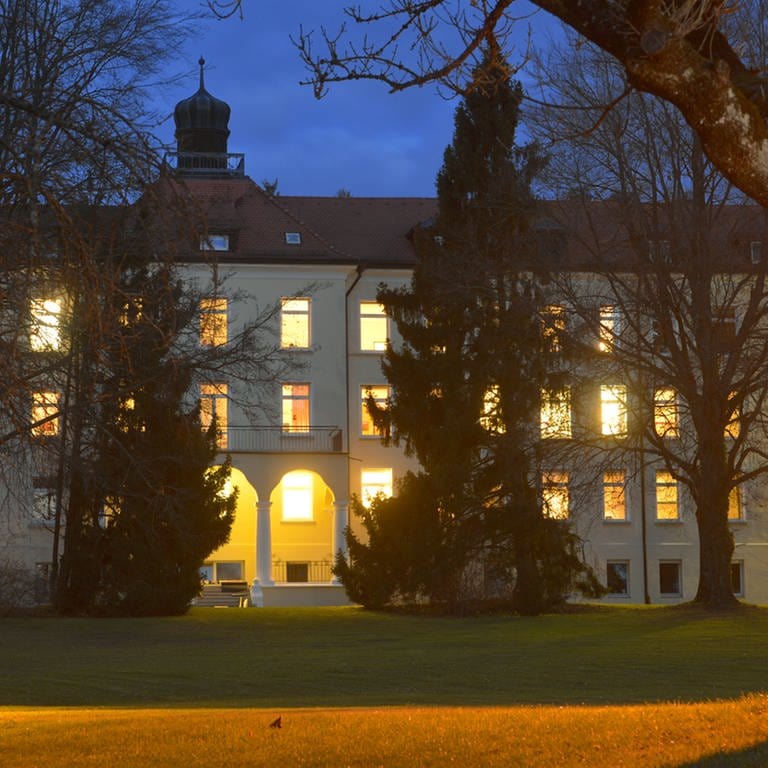 Das Bild zeigt das Krankenhaus Bad Waldsee bei Dunkelheit mit beleuchteten Zimmern.