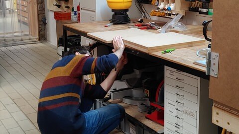 Foto: SWR Ein junger Mann in der Hocke an einer Werkbank (Foto: SWR)