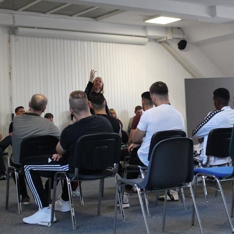 Gefangene in der JVA Bruchsal sind bei einem Poetry Slam. Der Slammer gestikuliert stark.