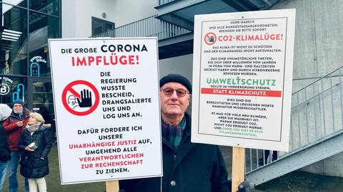 Mann aus Bad Wörishofen in Bayern, der mit seinen selbstgestalteten Schildern an der Querdenker Demonstration in Karlsruhe teilgenommen hat