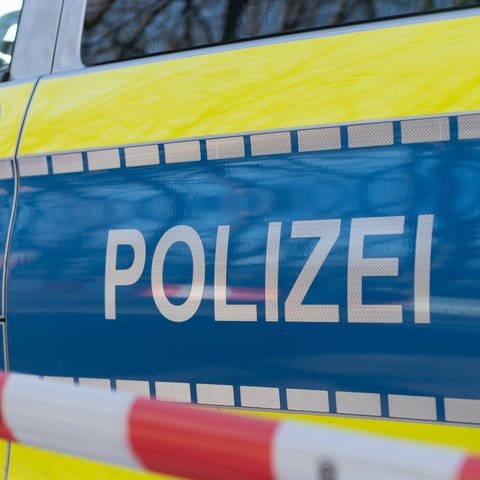 Symbolbild: Ein Polizeiauto mit einem Absperrband. In Straubenhardt im Enzkreis hat ein Brand ein Einfamilienhaus unbewohnbar gemacht.