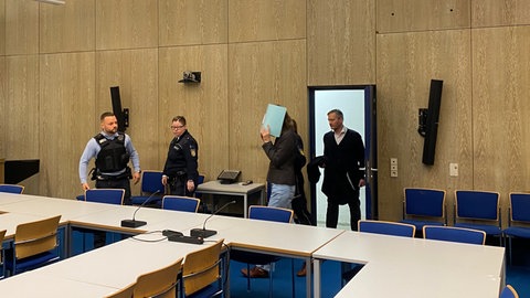 Die Angeklagte betritt den Gerichtssaal und verdeckt ihr Gesicht. (Foto: SWR) Die Angeklagte betritt den Gerichtssaal und verdeckt ihr Gesicht.
