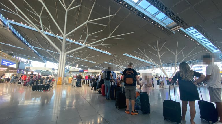 Fluggäste stehen in einem Terminal des Stuttgarter Flughafens.