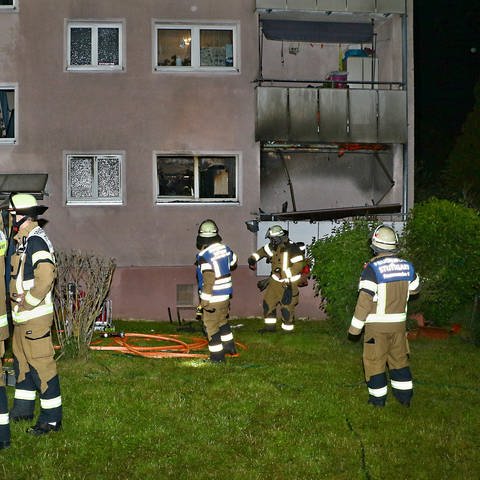 Feuerwehrleute stehen vor einem Mehrfamilienhaus in Stuttgart-Zuffenhausen, in dem am Pfingsmontag ein Brand ausgebrochen war.