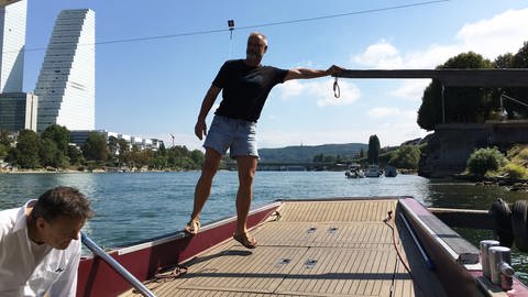 ein Mann in kurzen Hosen steht auf einem Boot und stößt sich ab
