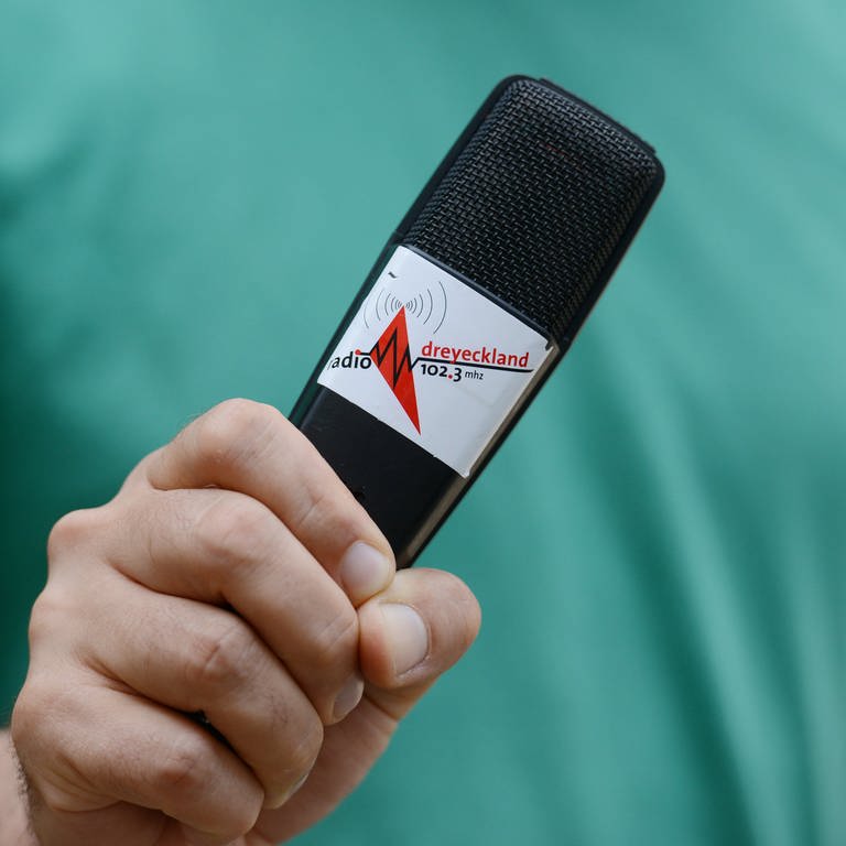 Archivbild - Der Pressesprecher von Radio Dreyeckland hält am 18.07.2013 ein Mikrofon in der Hand.