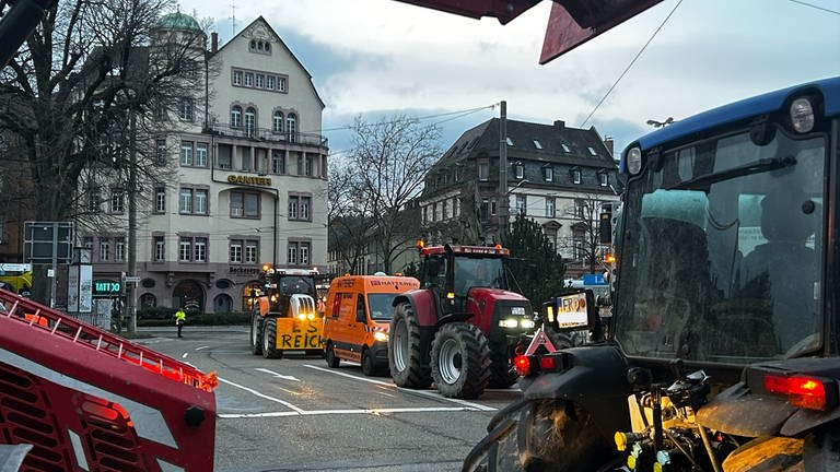 Auf einer Straßenkreuzung blockieren Traktoren von mehreren Seiten die Straße.
