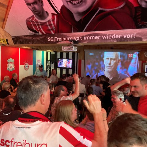 Alle schauen gespannt auf den Bildschirm: SC-Fans schauen in einer Freiburger Kneipe das letzte Spiel von Christian Streich.