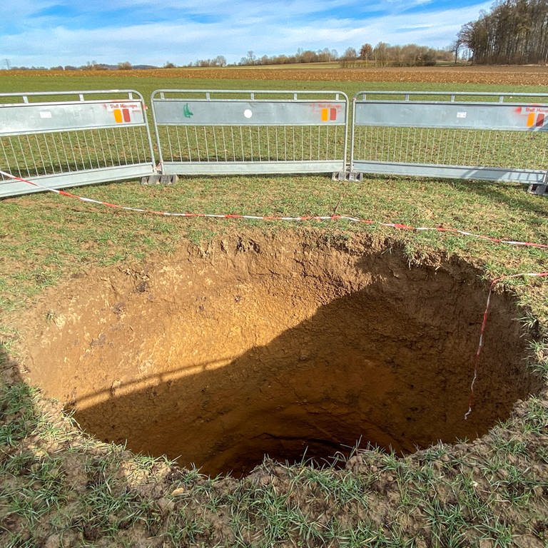 Auf einem Acker in der Nähe von Münsingen ist der Boden eingebrochen und hat eine Einsturzdoline von gut sieben Meter mit einem Durchmesser von drei Metern hinterlassen. Das Loch wurde mit Absperrzäunen gesichert.