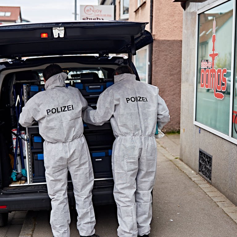 Zwei Polizisten an einem Auto vor dem Tatort. (Foto: Markus Brandhuber)