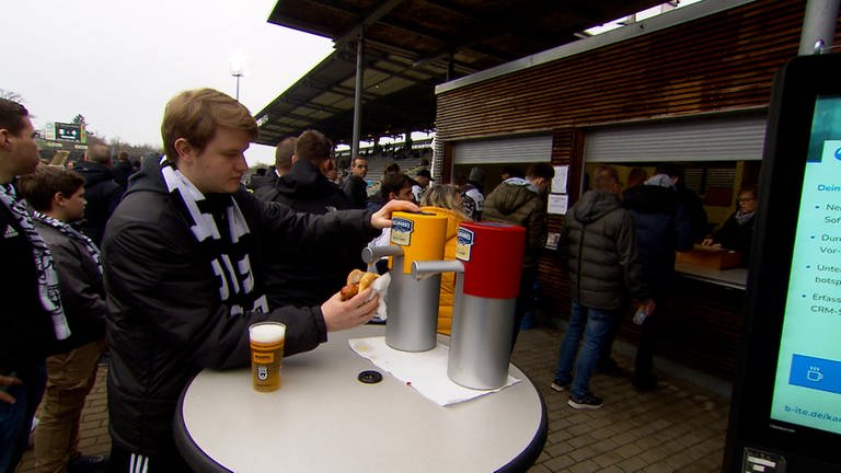 Ein Fan des SSV Ulm macht Senf auf seine Stadionwurst.