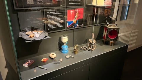 In einer Vitrine stehen mehrere Ausstellungsstücke. Es sind Werkzeuge aus der Steinzeit und der Neuzeit, die im Urgeschichtlichen Museum Blaubeuren ausgestellt werden.
