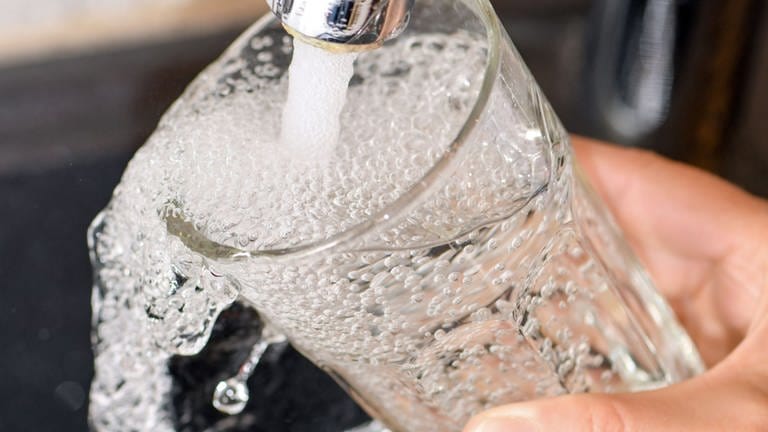 Symbolbild: Am Wasserhahn in einer Küche wird ein Trinkglas mit Leitungswasser befüllt.