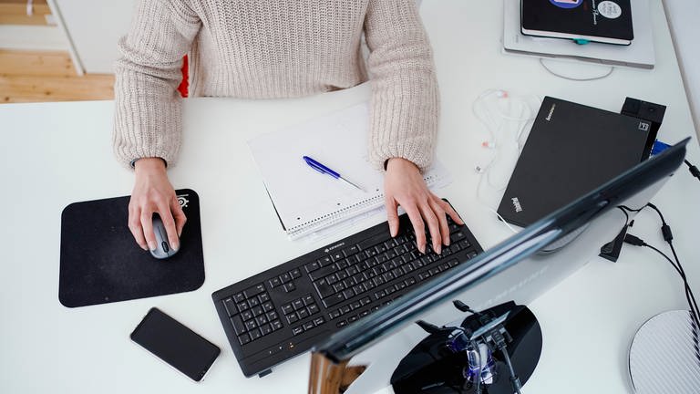 Eine Frau sitzt am Schreibtisch und arbeitet am Computer
