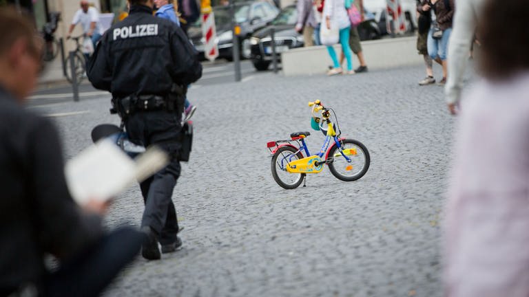 Eine Polizist geht am 21.06.2014 in Frankfurt am Main (Hessen) auf ein Kinderfahrrad zu. (Foto: dpa Bildfunk, picture alliance / dpa | Frank Rumpenhorst)
