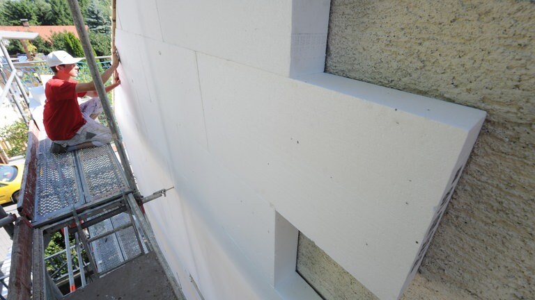 Ein Bauarbeiter bringt Dämmplatten an einer Hauswand an (Foto: dpa Bildfunk, picture alliance/dpa | Armin Weigel)