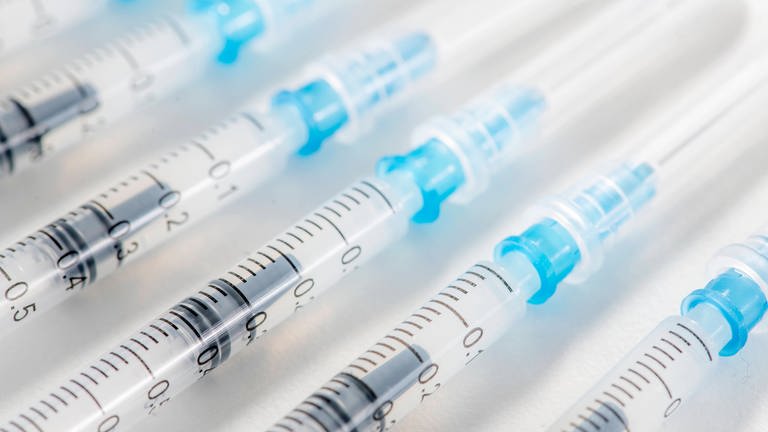 Foto von mehreren Impfspritzen mit BioNTech-Impfstoff vor weißem Hintergrund