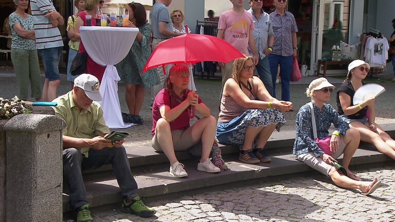 Menschen mit Sonnenschirm und Fächer, die sich vor der Hitze schützen
