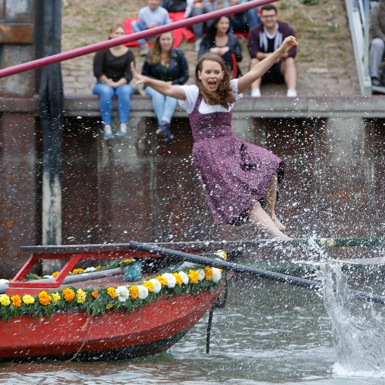 Junge Frau in Tracht fliegt beim "Fischerstechen" von ihrem Kahn