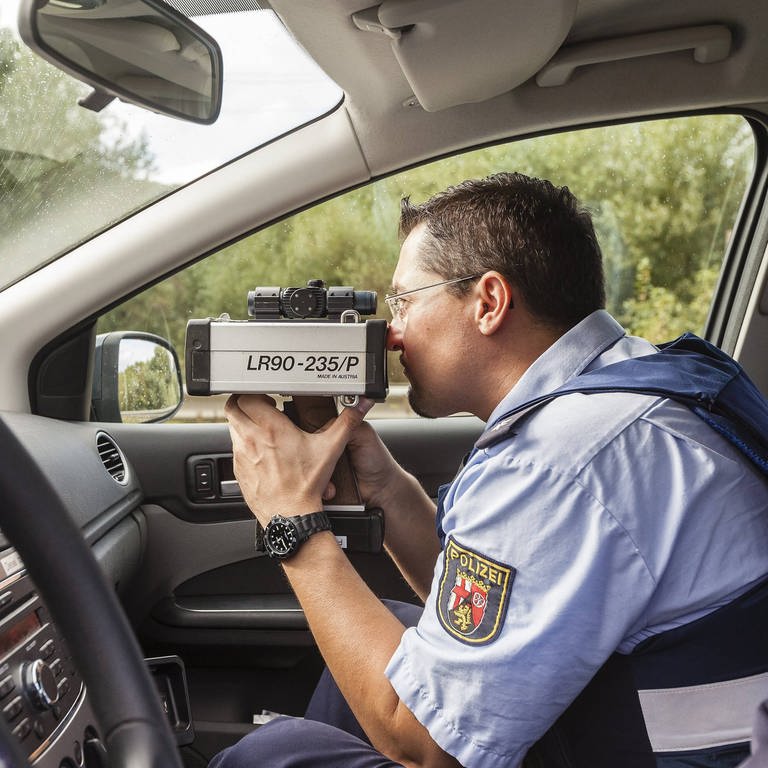 Polizist im Auto mit Radarfalle (Foto: IMAGO, IMAGO / Sascha Ditscher)
