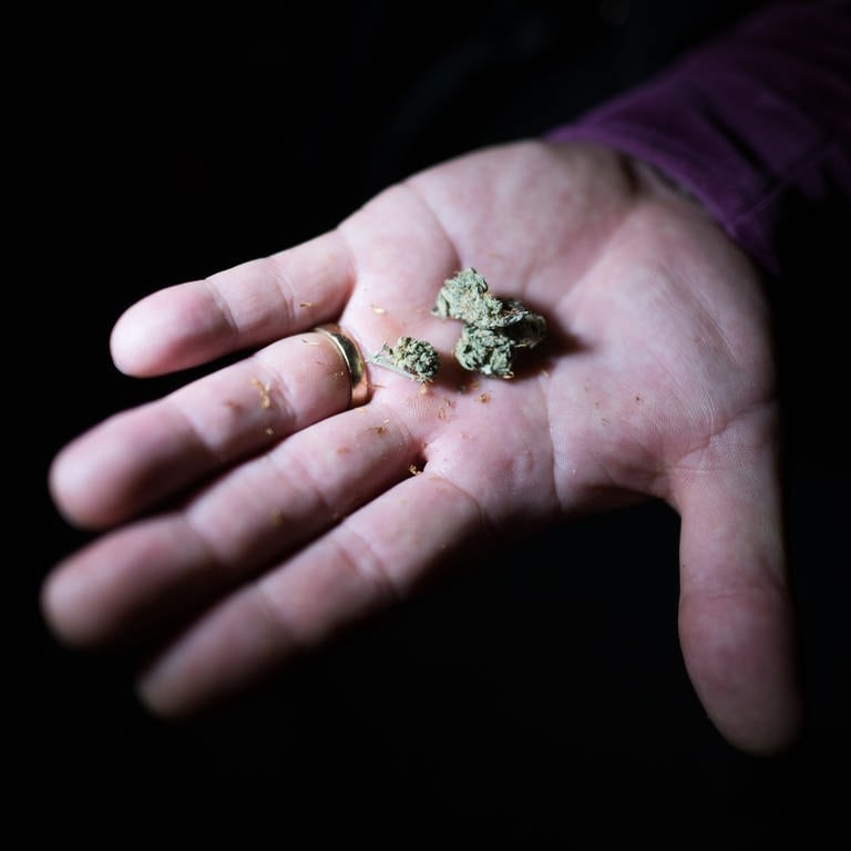 Ein Mann hält Cannabis in der Hand. 