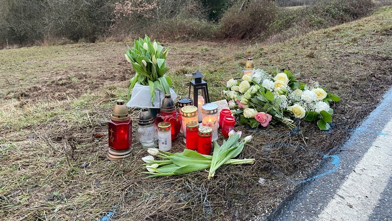 Nach dem Polizistenmord von Kusel liegen am Tatort Blumen und Kerzen am Straßenrand.
