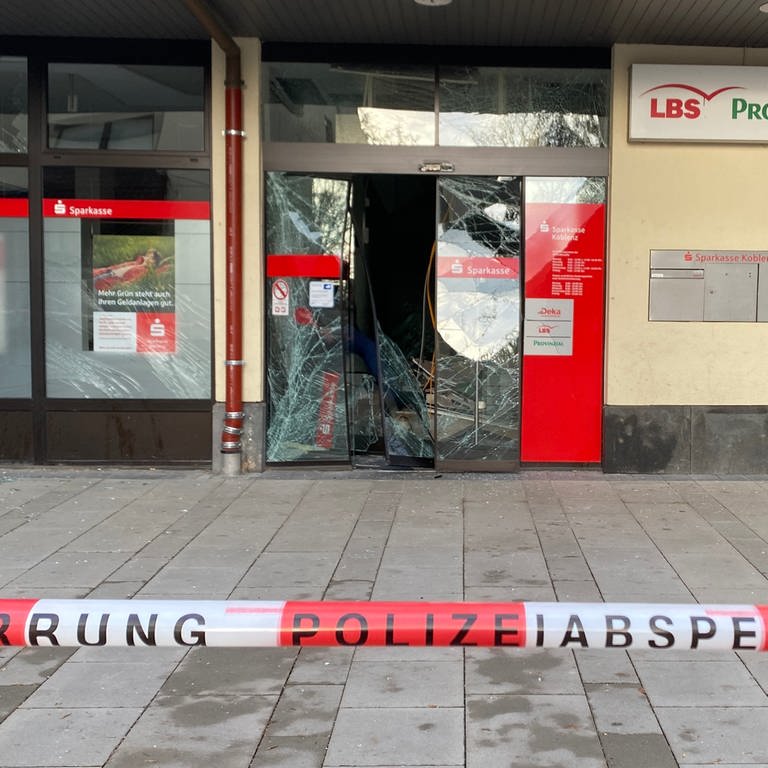 Eine zerstörte Glastür bei einer Sparkasse in Koblenz und eine Absperrung durch die Polizei
