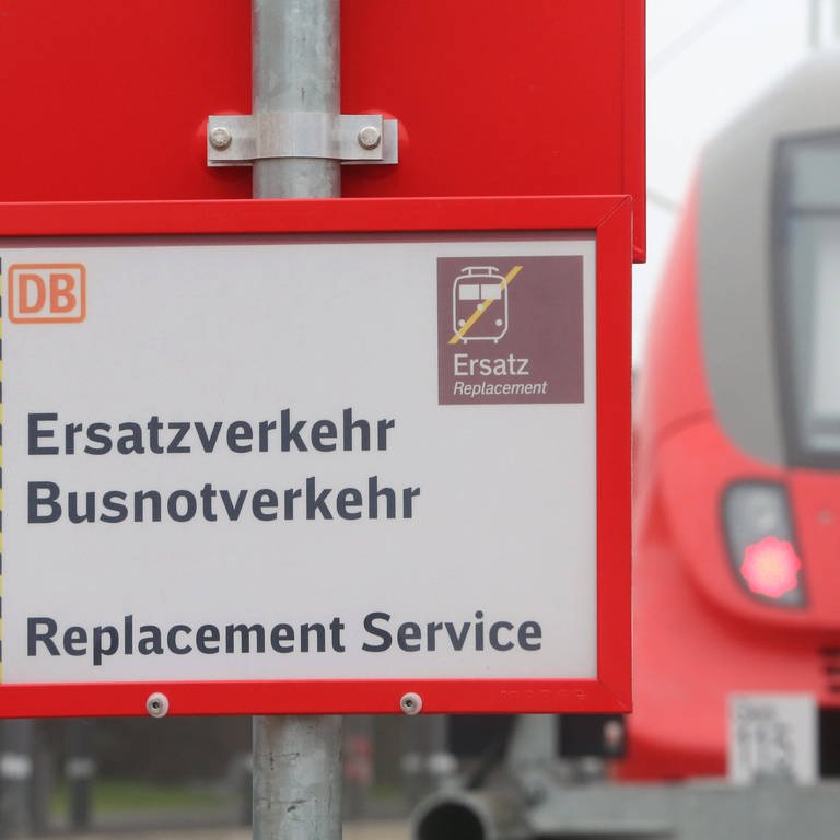 Blick auf einen Zug der Deutschen Bahn im Zusammenhang mit einem Schild das auf einen möglichen Ersatzverkehr hinweist. 