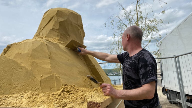 Mit einer Maurerkelle wird eine der Sandskulpturen in Neuwied vorgeformt