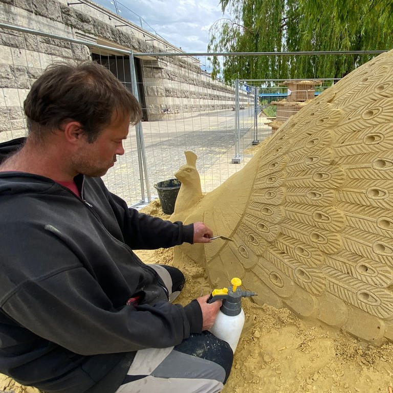 Einer der Künstler arbeitet an der Sandskulptur eines Pfaus, dem Neuwieder Wappentier. 