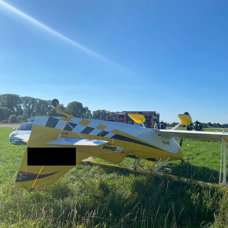 Ultraleichtflugzeug auf dem Rücken im Gras neben der Landebahn am Flugplatz Speyer