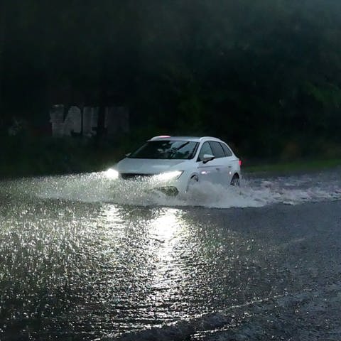 Drohendes Unwetter: Auto fährt über überflutete Straße