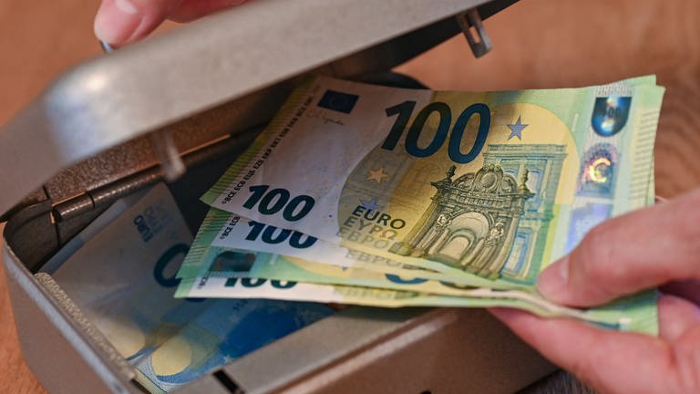 Eine Frau holt mehrere 100 Eurobanknoten aus einer kleinen Geldkassette. Die Aufnahme wurde für das Foto gestellt. 