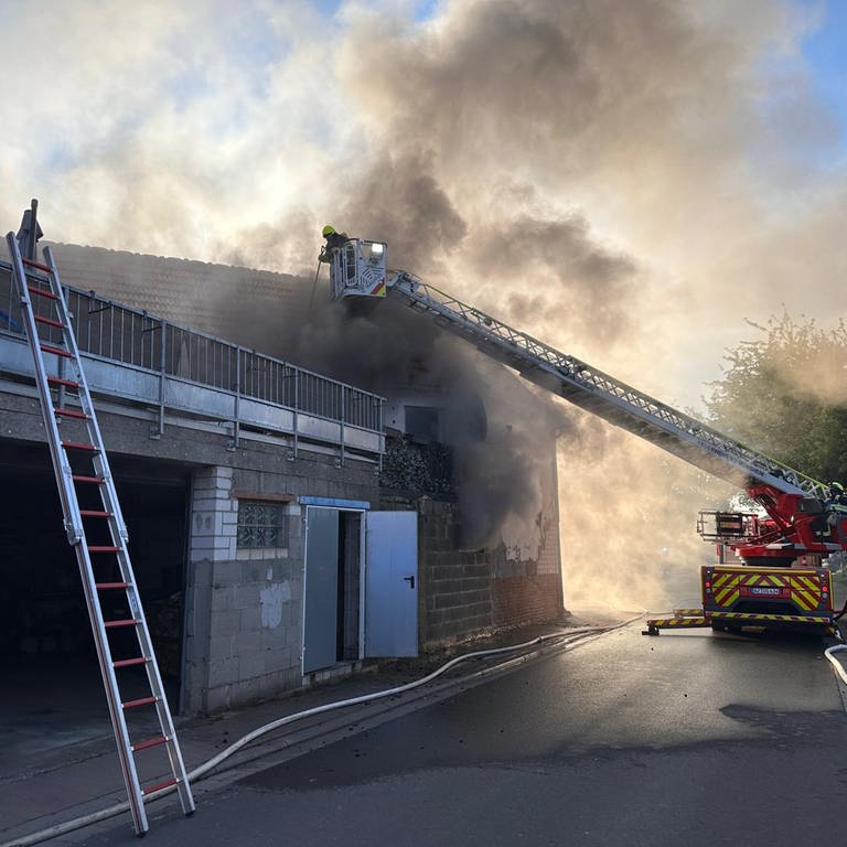 Rauch über dem Haus, ein Feuerwehrmann löscht von der Leiter aus: Brand in Dintesheim: Bewohner retten sich über Balkon