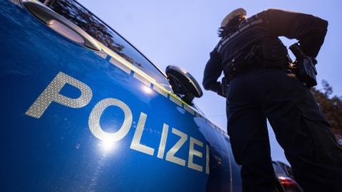 Ein Polizist vor einem Streifenwagen: Nach Schüssen auf eine Linienbus in Bad Kreuznach wurden zwei Tatverdächtige ermittelt