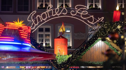 "Frohes Fest" leuchtet eine Schrift über dem Weihnachtsmarkt in Trier.  (Foto: dpa Bildfunk, picture alliance/dpa | Harald Tittel)