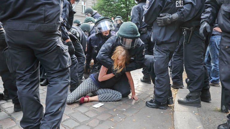 Festnahme einer jungen Frau während einer Protestaktion durch Polizeikräfte